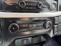 Interior dashboard controls of a 2021 Ford F-150 featuring climate control knobs and audio system buttons