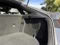 Interior view of the trunk of a 2024 Kia Forte5 showing the cargo space and two circular speakers mounted on the side wall