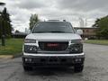 A 2012 GMC Canyon facing forward with a silver body and black lower front grille featuring a red GMC logo