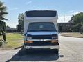 A 2020 Chevrolet Express with a white body and a black front grille parked on a road facing the camera