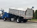 A blue 2017 Autocar Xpert truck with its dump bed raised displaying caution signs for frequent stops and wide right turns