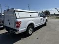 A white 2019 Ford F-150 pickup truck with a cap on the bed parked in a lot