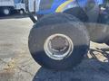 Close-up of a large, worn agricultural tire from a 2010 New Holland T4050 tractor showing visible tread wear and rust on the rim