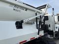 A 2013 International WorkStar truck with a white dump bed featuring a hydraulic lift mechanism and a side ladder for access to the bed