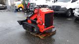 A red 2023 AGT Industrial compact track loader with a black front blade and tracks positioned on a wooden pallet