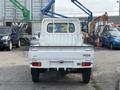 A white 2010 Daihatsu Hijet pickup truck viewed from the rear with a flatbed and a simple cabin design