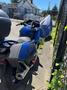 A blue 2016 Yamaha FJR1300AE motorcycle partially covered with a protective cover parked next to a fence