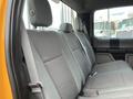 The interior back seat of a 2017 Ford F-250 SD with gray fabric upholstery and safety seat belts