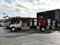 A white 2010 International 4300 truck with a red hydraulic lift on the back and storage compartments along the sides