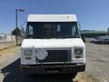 A white 2012 Ford Econoline van with a rectangular shape and a flat front end is parked in a lot with a missing front license plate