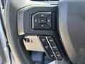 A close-up view of the steering wheel controls of a 2019 Ford F-150 featuring buttons for setting and adjusting cruise control and a central OK button