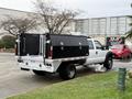 A 2016 Ford F-550 Super Duty with a white exterior and a custom black truck bed toolbox is parked at an angle