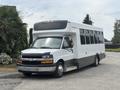 A white 2020 Chevrolet Express bus with large windows and a streamlined front design parked on a concrete surface
