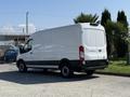 A 2022 Ford Transit van in white with a cargo area and rear doors slightly open, parked at an angle with a clear view of its sides and rear