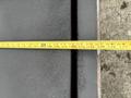 A measuring tape laid across a metal surface showing various measurement markings and a slight texture