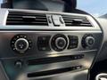 The image shows the interior controls of a 2004 BMW 6-Series featuring climate control dials and a CD player with a sleek metallic finish