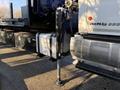 A close-up view of a 2015 Hino 358 truck showing the hydraulic lift system and stabilizing leg in the foreground