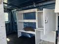 Interior of a 2005 Ford Econoline with metal shelving units and an open cabinet door