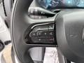 A close-up of the steering wheel controls of a 2023 RAM Promaster 3500 featuring phone and voice command buttons as well as navigation controls
