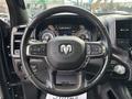 Steering wheel of a 2021 RAM 1500 with controls and the RAM logo prominently displayed in the center