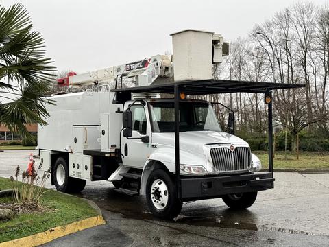 A 2020 International MV607 truck with a white exterior featuring an elevated work platform and a large utility box attached to the bed