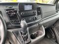 Interior view of a 2023 Ford Transit featuring a modern dashboard with a touchscreen display gear shift and climate control buttons