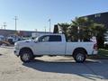 A white 2023 RAM 3500 pickup truck parked with chrome wheels and a spacious cab visible on the side