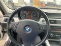 A 2011 BMW 3-Series steering wheel with controls and instrument cluster displaying various indicators and gauges