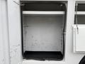 A 2012 Ford F-450 SD with an open storage compartment featuring a clean interior shelving unit and a black base