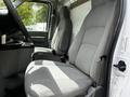 Interior of a 2018 Ford Econoline showing two gray cloth front seats with a center console and seat belts