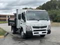 A 2015 Mitsubishi Fuso FE160 truck with a dump bed and a box on the back positioned on a paved surface