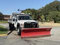 A 2008 Ford F-450 SD pickup truck with a large red snow plow attached to the front