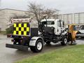 A 2016 Freightliner 108SD truck with a snow plow attached and a yellow and black checkerboard design on the back