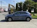 A 2018 Kia Rio5 parked on asphalt featuring a blue exterior and hatchback design with five doors and alloy wheels