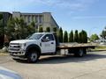 2022 Ford F600 flatbed truck in white with a wide cargo bed and a sturdy front grille parked on a concrete surface