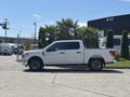 A white 2021 Ford F-150 with a crew cab and black alloy wheels is parked side profile on a paved surface