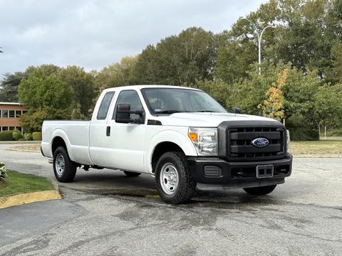 A white 2011 Ford F-250 SD pickup truck with a black grill and front bumper is parked on a driveway facing forward