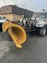 A 2007 International 7300 truck equipped with a large yellow snow plow blade attached to the front