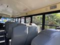 Interior of a 2013 International CE300 school bus showing rows of grey seats with large windows offering views of greenery outside