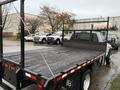 A 2008 Sterling Bullet flatbed truck with a wooden bed and metal sides is parked, showing no cargo and featuring a mesh guard at the back