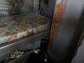 Interior of a 2009 Peterbilt Highway truck featuring a patterned mattress on the lower bunk and brown wood paneling on the side