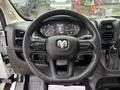 Steering wheel of a 2023 RAM Promaster 3500 featuring the RAM logo and various control buttons on the spokes along with a digital dashboard display in the background