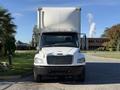 A white 2012 Freightliner M2 106 truck with a large cargo box at the back is facing the viewer directly
