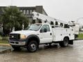 A 2006 Ford F-450 bucket truck with a white exterior featuring a raised hydraulic boom and storage compartments on the side