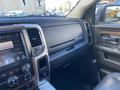The interior of a 2017 RAM 1500 featuring a dashboard with a touchscreen display climate controls and wood accents with a view of the driver's side door panel