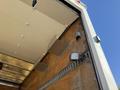 The interior of a 2014 Hino 195 truck showing wooden panels and metal supports with a mounted light fixture on the wall