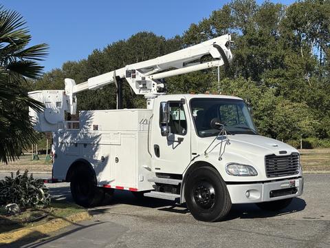 A white 2006 Freightliner M2 106 bucket truck with an extended aerial lift and side compartments for tools and equipment