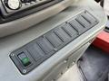A control panel with multiple switches and a green button on a 2002 Ford Econoline dashboard