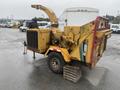 A yellow 2010 Vermeer Corporation BC1000XL wood chipper with a large feeding chute and a trailer hitch sits on a wooden pallet