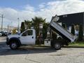 A white 2008 Ford F-550 dump truck with the bed raised is shown in profile, showcasing its large wheels and sturdy construction